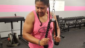 A woman performing tricep push-downs during a workout.