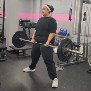 Woman performing a sumo deadlift with a barbell in a personal training session in a Richmond gym
