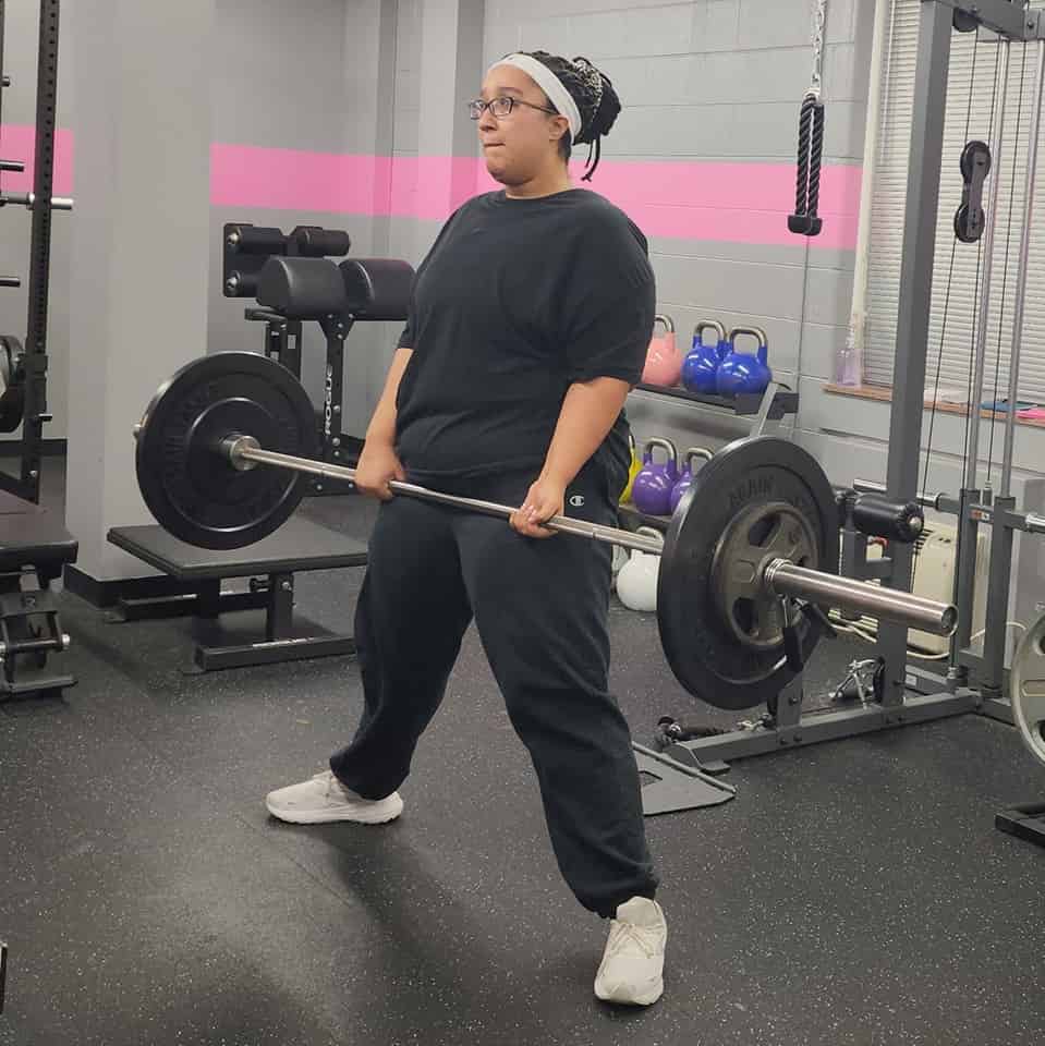 Woman performing a sumo deadlift with a barbell in a Richmond gym