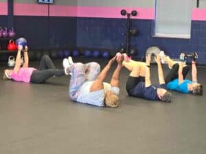 Four Glatter Fitness members performing a floor exercise with kettlebells and dumbbells during a small group personal training class in Richmond, VA.