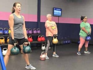 Diverse group of women of all fitness levels performing kettlebell exercises at Glatter Fitness.