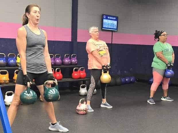 Diverse group of women of all fitness levels performing kettlebell exercises at Glatter Fitness.