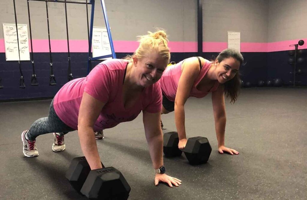 Two women performing plank exercises with dumbbells in a Glatter Fitness bootcamp session in Richmond.