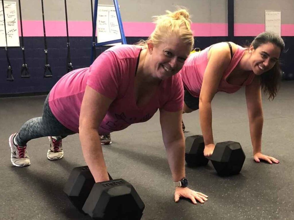 Two women performing plank exercises with dumbbells in a Glatter Fitness gym in Richmond.