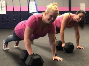 Two women performing plank exercises with dumbbells in a Glatter Fitness gym in Richmond.