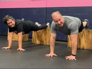 Two Glatter Fitness members performing elevated push-ups on plyo boxes as part of a partner functional training workout in Henrico.