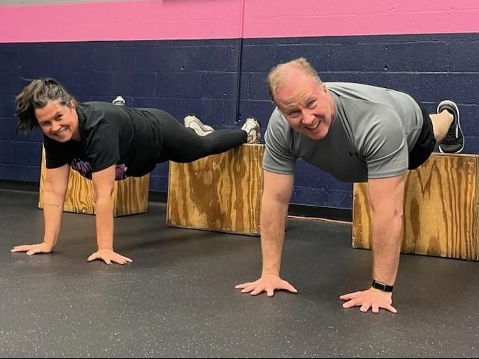 Two Glatter Fitness members performing elevated push-ups on plyo boxes as part of a partner functional training workout in Henrico.