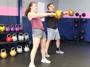Clients performing kettlebell swings, demonstrating balanced strength training and cardio workout.