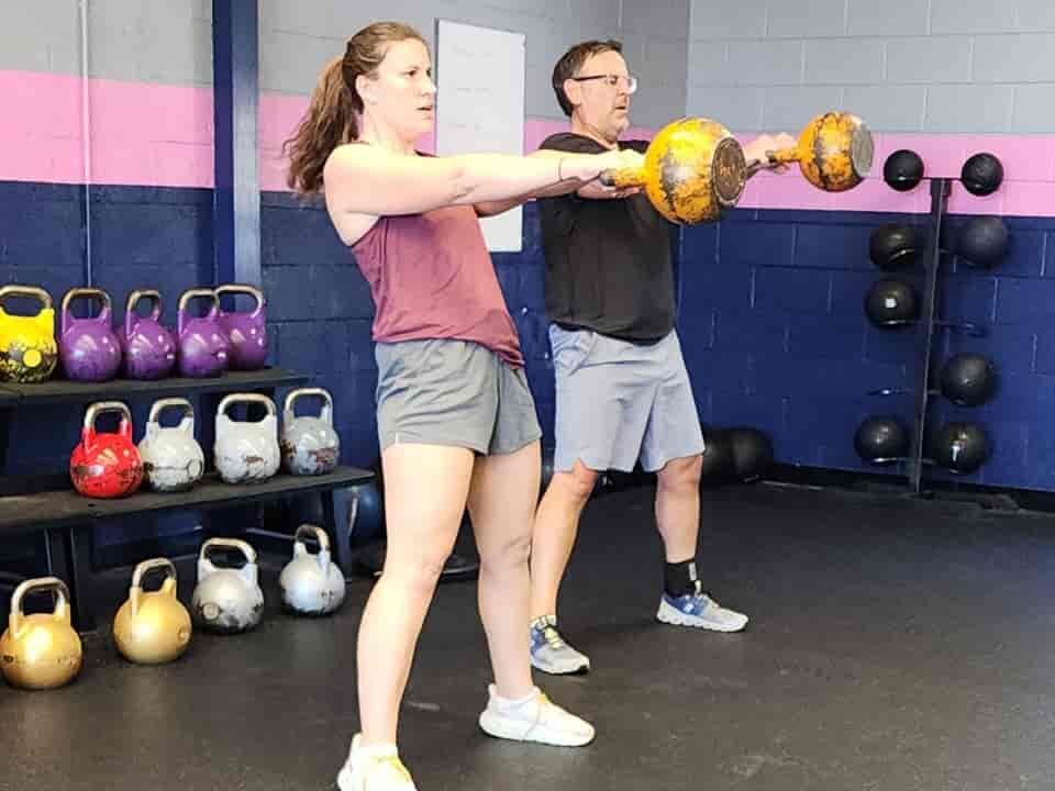 Clients performing kettlebell swings, demonstrating balanced strength training and cardio workout.