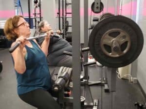 Two Glatter Fitness clients performing functional strength training exercises in a supportive team environment.